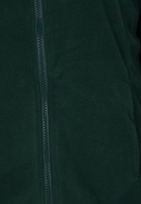 Giacca in pile verde scuro con una texture liscia e una cerniera verticale. Presenta una leggera lucentezza e nessun motivo o accento visibile.