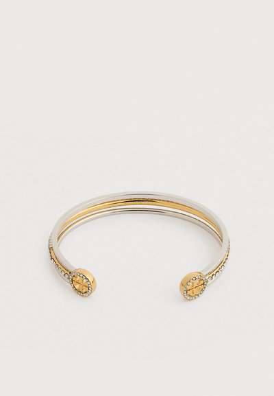 Dvivietis atviras apyrankis su auksiniais galais, kuriame yra logotipas, apsuptas mažų skaidrių Kristalų ant baltos fono.