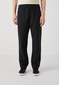 Pantalon noir, ample, avec une taille élastique et un cordon de serrage. Fabriqué en tissu doux, il présente des poches latérales et une coupe droite.