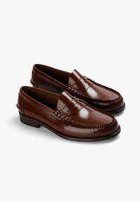 Mocasines de cuero marrón con un acabado brillante, que presentan un detalle cosido en el frente y un tacón bajo para soporte y comodidad.