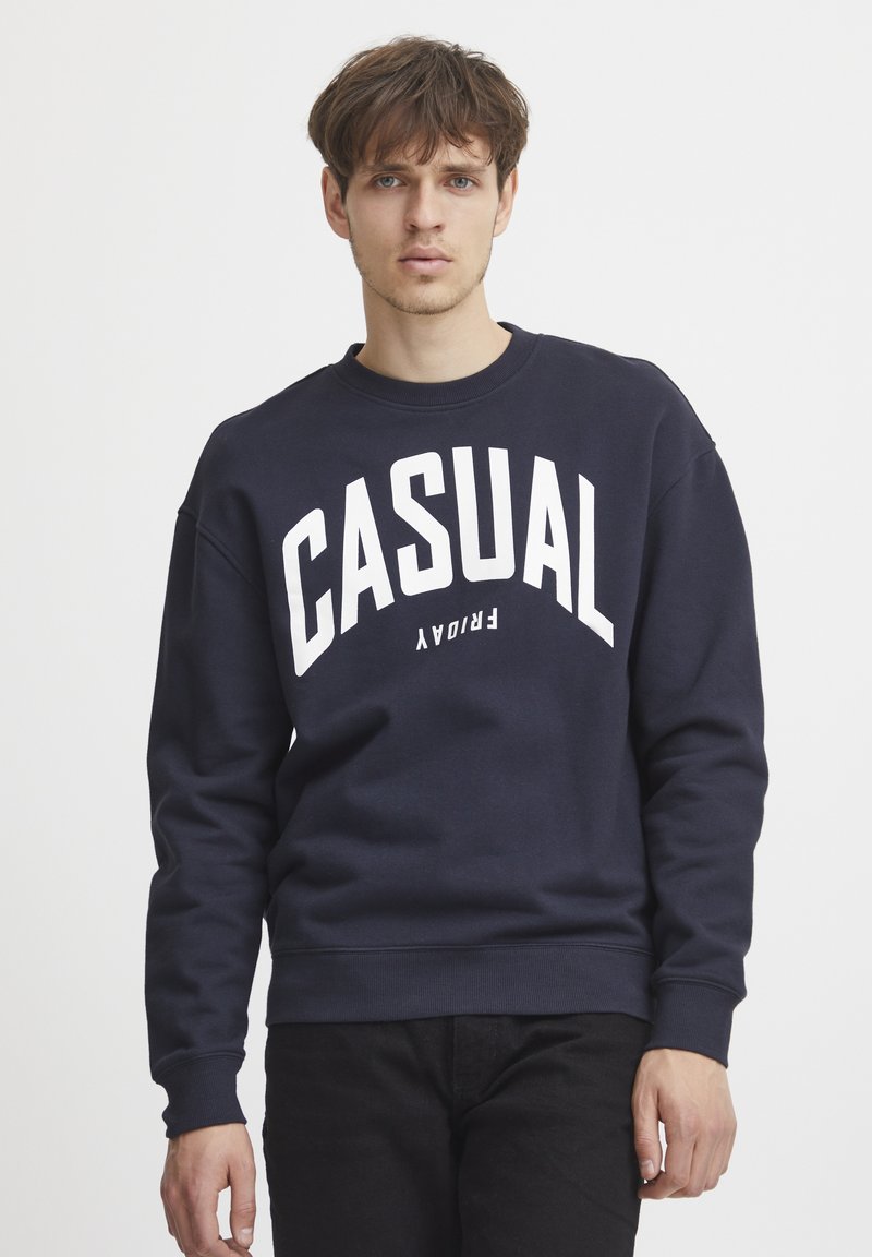 Marineblauwe crewneck sweatshirt van een katoenmix, met grote witte tekst "CASUAL" op de voorkant, en geribde manchetten en zoom.