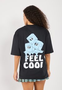 Schwarzes, übergroßes T-Shirt mit drei Cartoon-Eiswürfeln mit Gesichtern und dem Text "FEEL COOL" in fettem Weiß darunter.