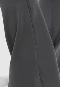 Pantaloni in tessuto elasticizzato nero con una trama liscia, caratterizzati da una cucitura prominente che corre verticalmente lungo il lato per un ulteriore dettaglio di design.