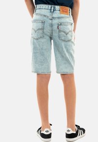 Helle blaue Denim-Shorts mit einer ausgewaschenen Optik, Fünf-Taschen-Design und einem braunen Leder-Patch. Mit gestickten Gesäßtaschen und geradem Schnitt.