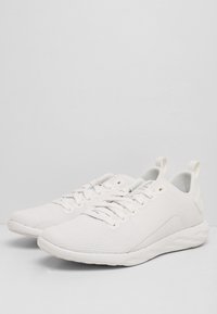 Witte sportschoenen met een gestructureerde mesh bovenkant, afgeronde neus, vetersluiting en een gevoerde zool. Voorzien van een trekhaak aan de hiel.