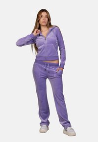 Lavender tracksuit made of soft, velour fabric; zip-up hoodie with front pockets, matching pants featuring an elastic waistband and side pockets.