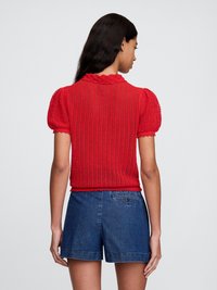 Rød avkortet topp med teksturert, strikket design og pufferm; parret med denimshorts med baklomme og oppbrettede kanter.