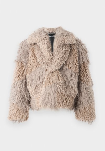 Kailinys kailio švarkas smėlio spalvos, su pūkine tekstūra, plačiu apykakle ir trumpu kirpimu. Yra skirtingų ilgių kailių, sudarančių skirtingų fragmentų raštą.