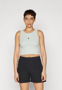 Lys grå ribbet crop-topp med rund hals og liten logo på brystet, kombinert med svarte cargo-shorts med sidelommer.