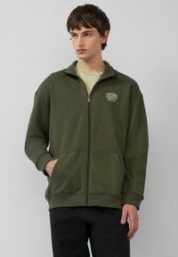 Olivgrüner Zip-Hoodie aus Baumwollmischung mit hohem Kragen, Seitentaschen und kleinem Logo auf der linken Brust.
