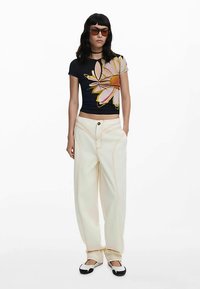 Granatowy kwiatowy krótki top z wycięciem w kształcie łezki; kremowe spodnie o szerokich nogawkach z pomarańczowym przeszyciem; czarno-białe buty; brązowe okulary przeciwsłoneczne.