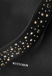 Czarna skórzana torebka z ozdobnym paskiem, na którym znajdują się różne metalowe ćwieki w kolorach złotym, srebrnym i czarnym. Nazwa marki "Wittchen" wytłoczona.