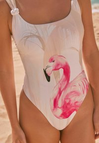 Eén stuk badpak in het wit met een roze flamingo grafiek. Kenmerkt geknoopte banden en een slank, aansluitend ontwerp met een hoge uitsnede bij het been.