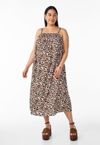 Abito lungo in stampa leopardata con spalline regolabili. Tessuto leggero, corpetto arricciato, vestibilità comoda. Indossato con sandali con plateau marroni.