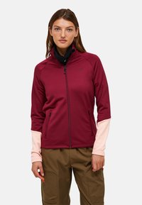 Burgundy zip-jakke med pink accenter og sidelommer, lavet af et blødt stof; har en høj krave og en tætsiddende design.