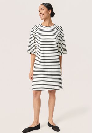 Striped short-sleeve dress in black and white, loose fit, round neckline, knee-length, fabric has a smooth texture, paired with black flats.
