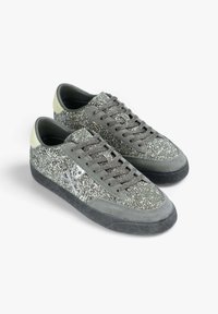 Gray glitter sneakers with a smooth suede finish, contrasting lime green accents, and dark rubber soles. Features lace closure and logo detail.