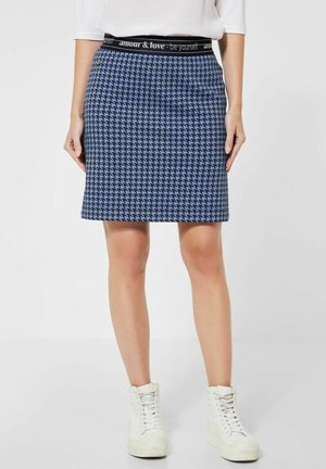 Sininen ja musta houndstooth-hamonen mustalla vyötäröllä, jossa on teksti "amour & love - be yourself." Keskipituinen malli, jossa on istuva siluetti.