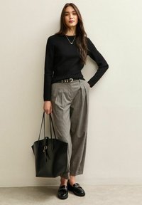 Zwart geribbeld truitje, grijs geblokt high-waisted broek met een riem, zwarte tote bag en glanzende zwarte loafers. Eenvoudige, moderne outfit.
