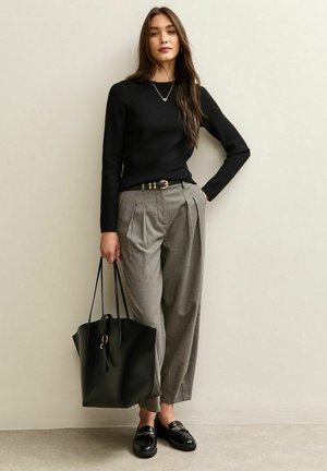 Zwart geribbeld truitje, grijs geblokt high-waisted broek met een riem, zwarte tote bag en glanzende zwarte loafers. Eenvoudige, moderne outfit.