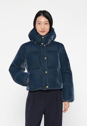 Giacca imbottita blu navy in morbido tessuto peloso con colletto alto e staccabile e bottoni dorati, caratterizzata da sezioni trapuntate e un design cropped.