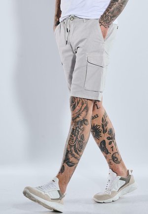 Light gray cargo shorts with side pockets, made from durable fabric. Pairing with white and beige sneakers featuring mesh detailing.