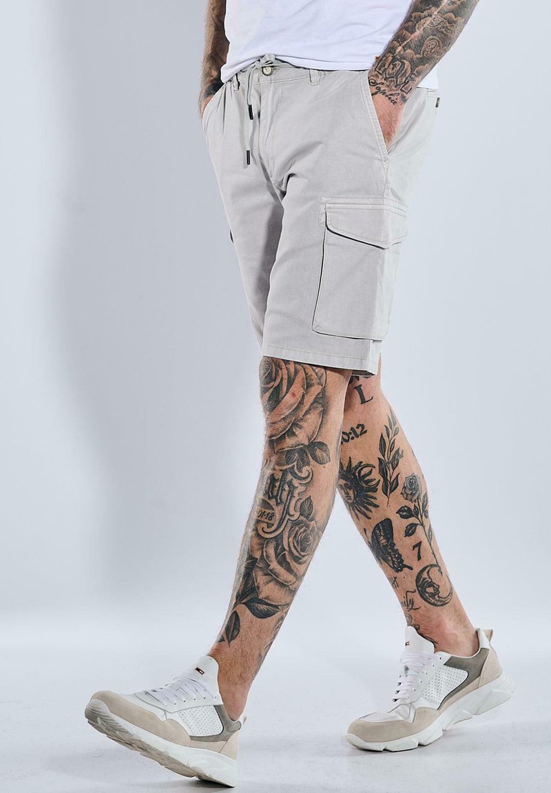 Light gray cargo shorts with side pockets, made from durable fabric. Pairing with white and beige sneakers featuring mesh detailing.