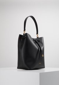 Sac seau en cuir noir avec une forme décontractée, une poignée simple, une fermeture à cordon et des accents en métal doré. Texture lisse.