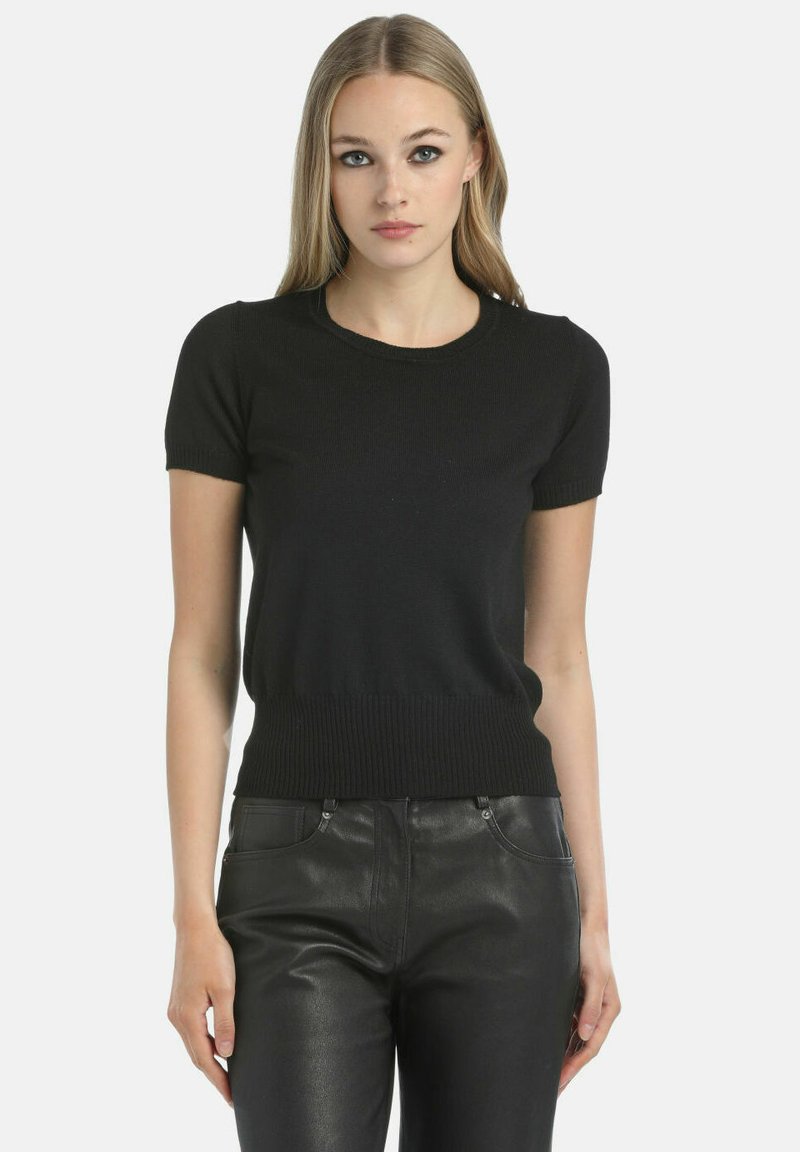 Juodas megztinis trumpomis rankovėmis su apvaliu iškirpimu ir banguotu sijonu, derinamas su juodomis odinėmis kelnėmis. Lygus paviršius visame megztinyje.