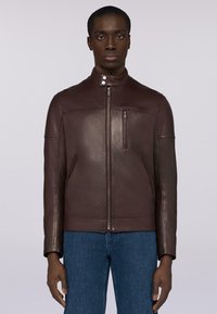 Bruine leren jas met een hoge kraag, rits aan de voorkant en zijzakken. Heeft een gladde textuur en minimalistische designelementen.