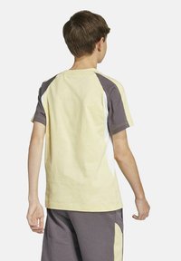 Kurzarm-T-Shirt mit gelben und grauen Paneelen, rundem Hals und atmungsaktivem Stoff, der für Komfort und Beweglichkeit konzipiert ist.