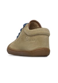 Scarpa in suede beige con punta arrotondata, suola in gomma marrone e lacci blu. Presenta un rilievo sul tallone e una superficie morbida e texture.