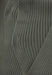 Tissu tricoté côtelé d'un vert olive foncé, présentant un motif texturé et un matériau doux et flexible qui tombe en douceur.