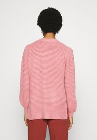 Maglione a coste rosa con scollo rotondo e maniche lunghe, caratterizzato da una vestibilità morbida e un motivo testurizzato.