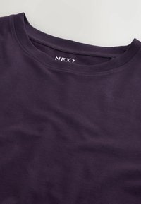 Fialové bavlněné tričko s kulatým výstřihem, které má hladkou texturu. Značkový štítek "NEXT" je výrazně umístěn na výstřihu.