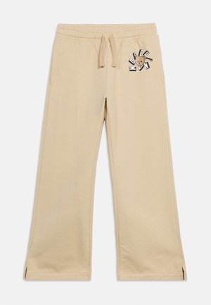 Beige wide-leg sweatpants with elastic waistband, drawstring, side pockets, and teddy bear logo with "Moschino" text on left hip.