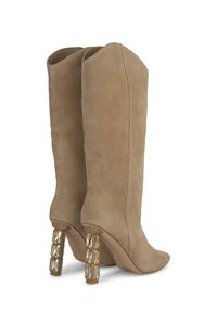 Bottes en suède beige jusqu'au genou avec un bout pointu et des talons à colonne transparents accentués de cristaux. Texture lisse, design minimaliste.