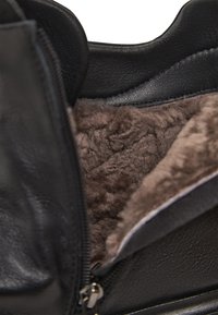 Zwarte leren laars met een ritsluiting, voorzien van een zachte bruine nepbont voering en een gladde textuur. Het interieur toont pluizige details.