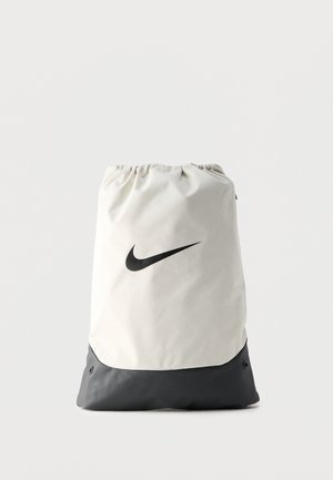 Valge ja hall Nike kotti siduv seljakott musta Swoosh logo keskel esiküljel, taust on lihtne.
