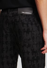 Jeans negri cu un model texturat, design cu cinci buzunare și o etichetă din piele neagră cu "KARL LAGERFELD" pe talie.