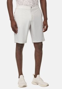 Shorts gris clair au tissu lisse, dotés de poches latérales et d'une fermeture à bouton, associés à des chaussures de sport blanches.