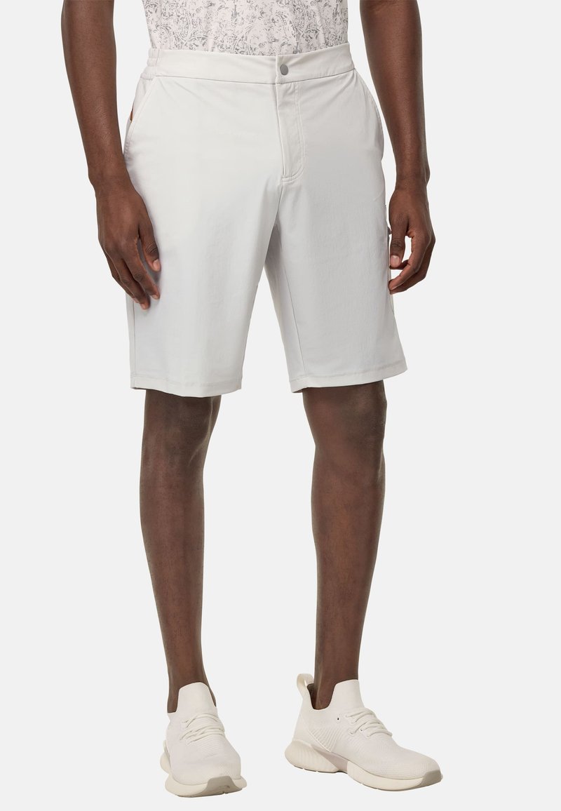 Shorts gris clair au tissu lisse, dotés de poches latérales et d'une fermeture à bouton, associés à des chaussures de sport blanches.