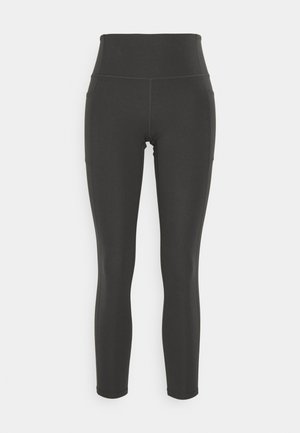 Hoge zwarte legging van rekbare stof met een gladde textuur; voorzien van zijzakken en platte naden voor extra comfort.