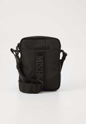 Geantă compactă de umăr neagră cu curea ajustabilă și logo-ul vertical MOSCHINO pe panoul central frontal, pe un fundal alb.
