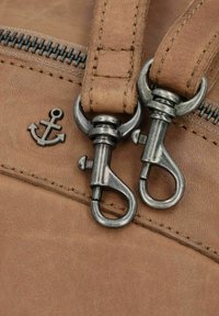 Borsa in pelle marrone con superficie testurizzata, dotata di zip in metallo e un piccolo emblema di ancora sulla parte anteriore.