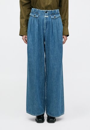 Παντελόνι τζιν με φαρδιά παντελόνα σε ανοιχτό μπλε χρώμα. Διαθέτει πιέτες στη μέση, δυο μπροστινές τσέπες και κούμπωμα με κουμπί. Το ύφασμα έχει λεία υφή.