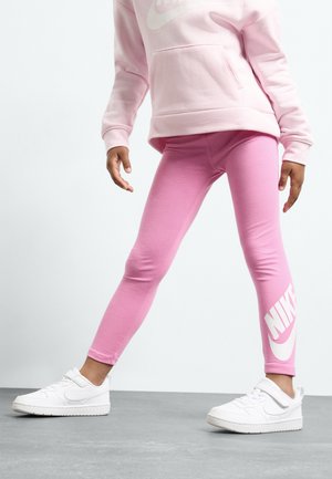 Różowe legginsy bawełniane z białym logo Nike na dolnej części nogawki, w zestawie z białymi sneakersami i dopasowaną różową bluzą z kieszeniami.