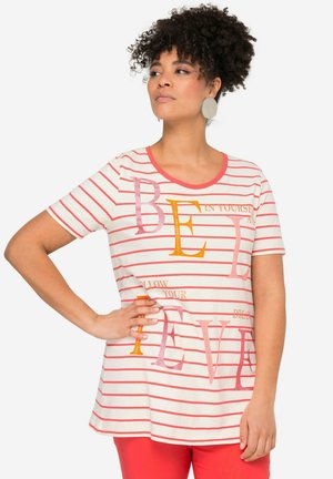 Hvidstribet t-shirt med rød og orange tekst, rund halsudskæring, korte ærmer og afslappet pasform. Bæres med røde bukser.