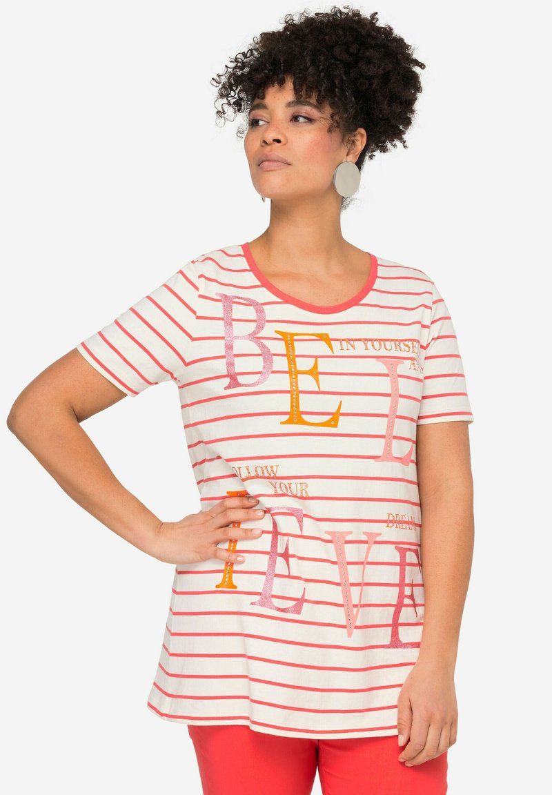 Hvidstribet t-shirt med rød og orange tekst, rund halsudskæring, korte ærmer og afslappet pasform. Bæres med røde bukser.