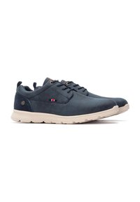 Zapatos de ante azul marino con punta redonda, con cierre de cordones, suela de goma beige y un pequeño acento de logo en rojo, blanco y azul.